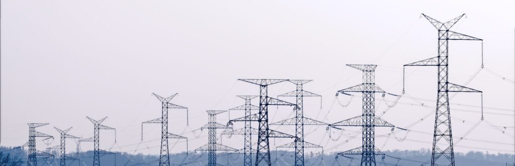 Row of high-voltage transmission pylons carrying power lines across countryside